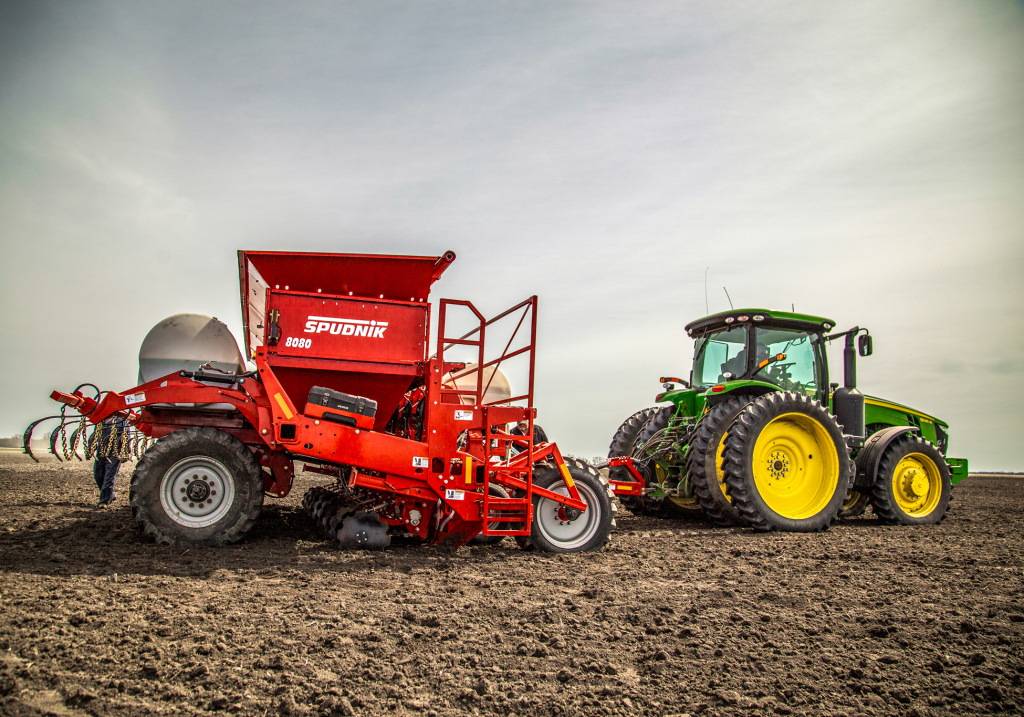 Spudnik's 8 Row Potato Planter with John Deere tractor being used in a farm.