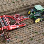 Piece of farming equipment and a John Deere tractor digging potatoes