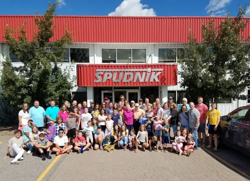 Carl Hobbs, Co-founder of Spudnik Equipment Company with his extended family posing for a picture in front of a Spudnik Equipment's main office.